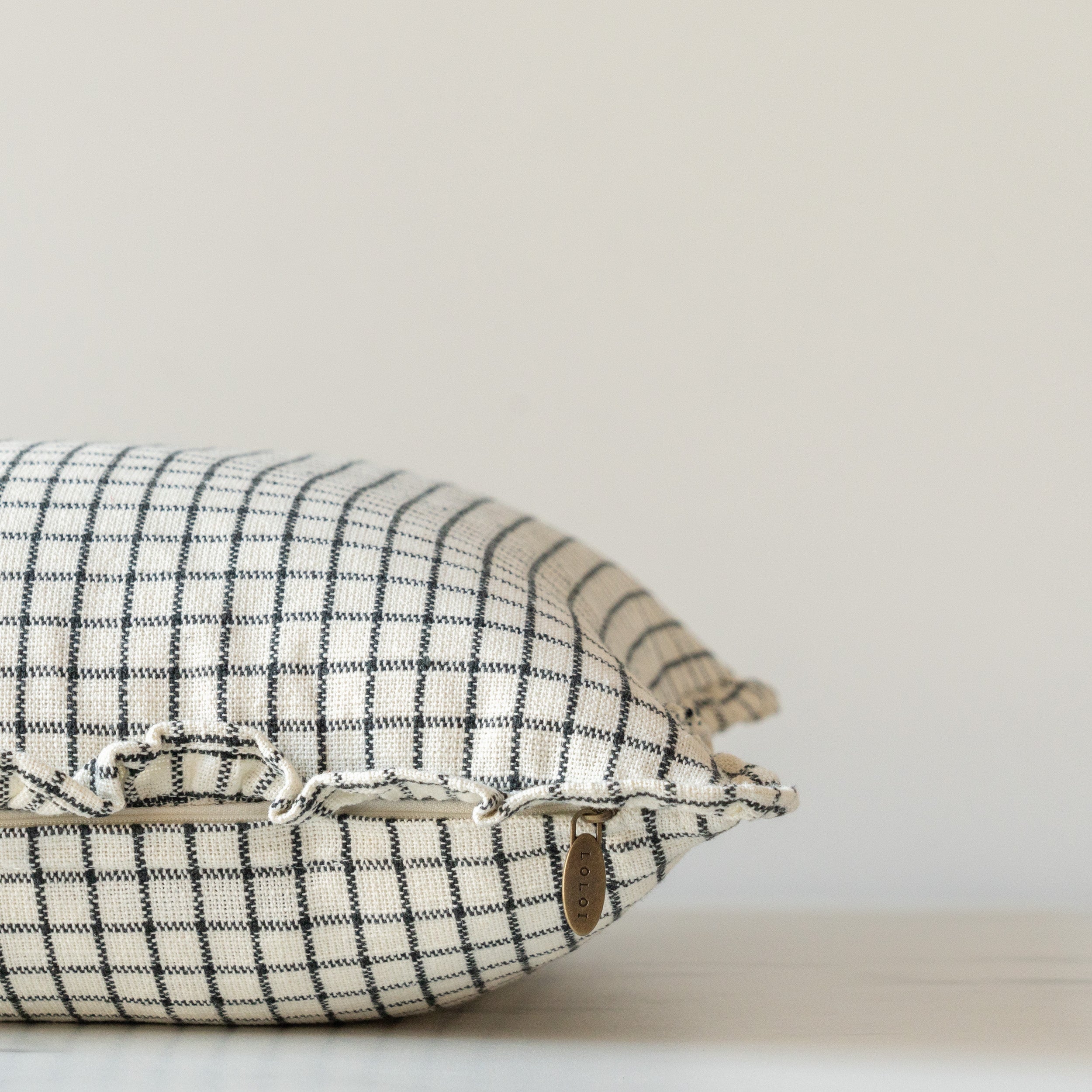 White and black grid ruffle pillow with invisible zipper closure with brass pull.