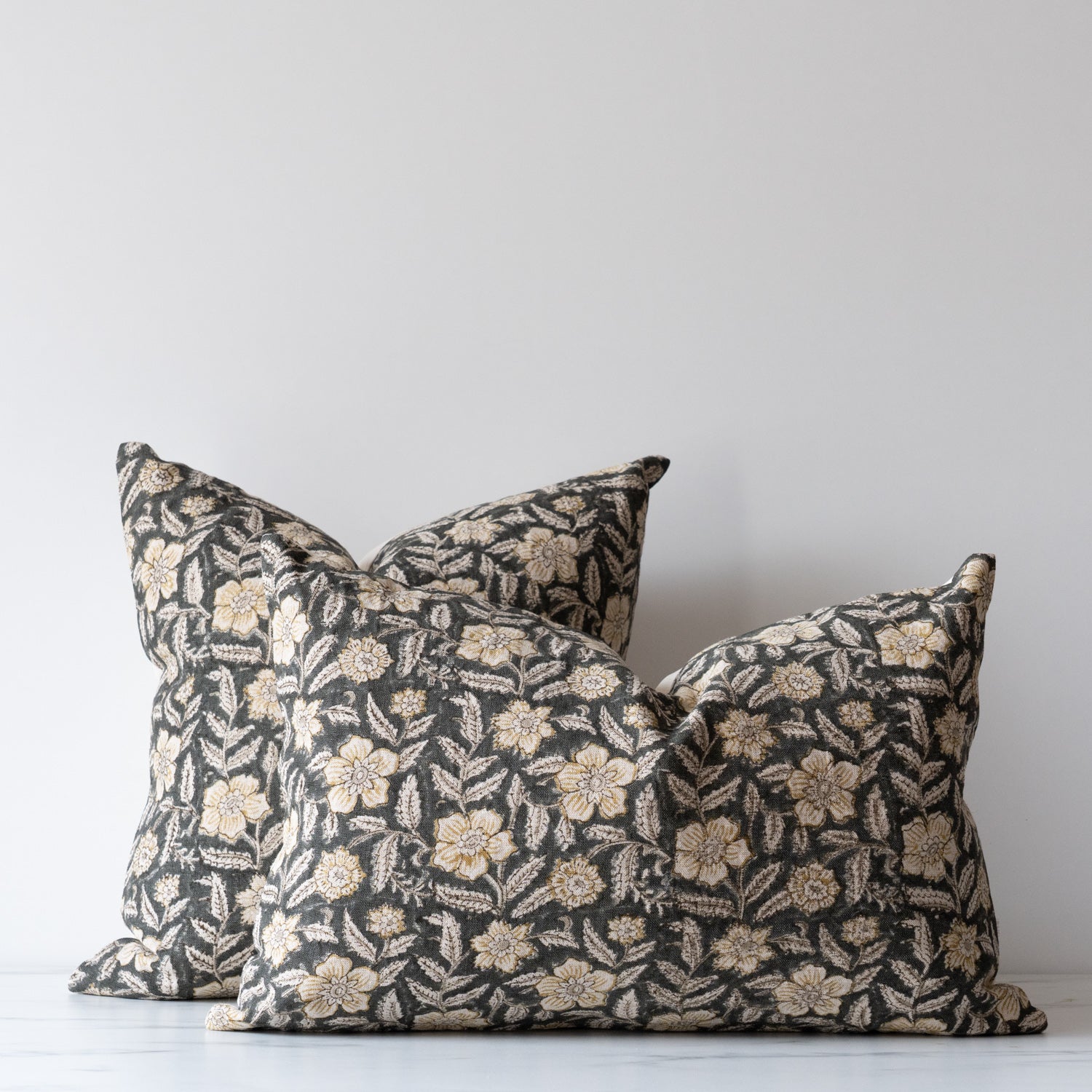 Square and lumbar block print pillow covers in green, with yellow and off white flowers and leaves.