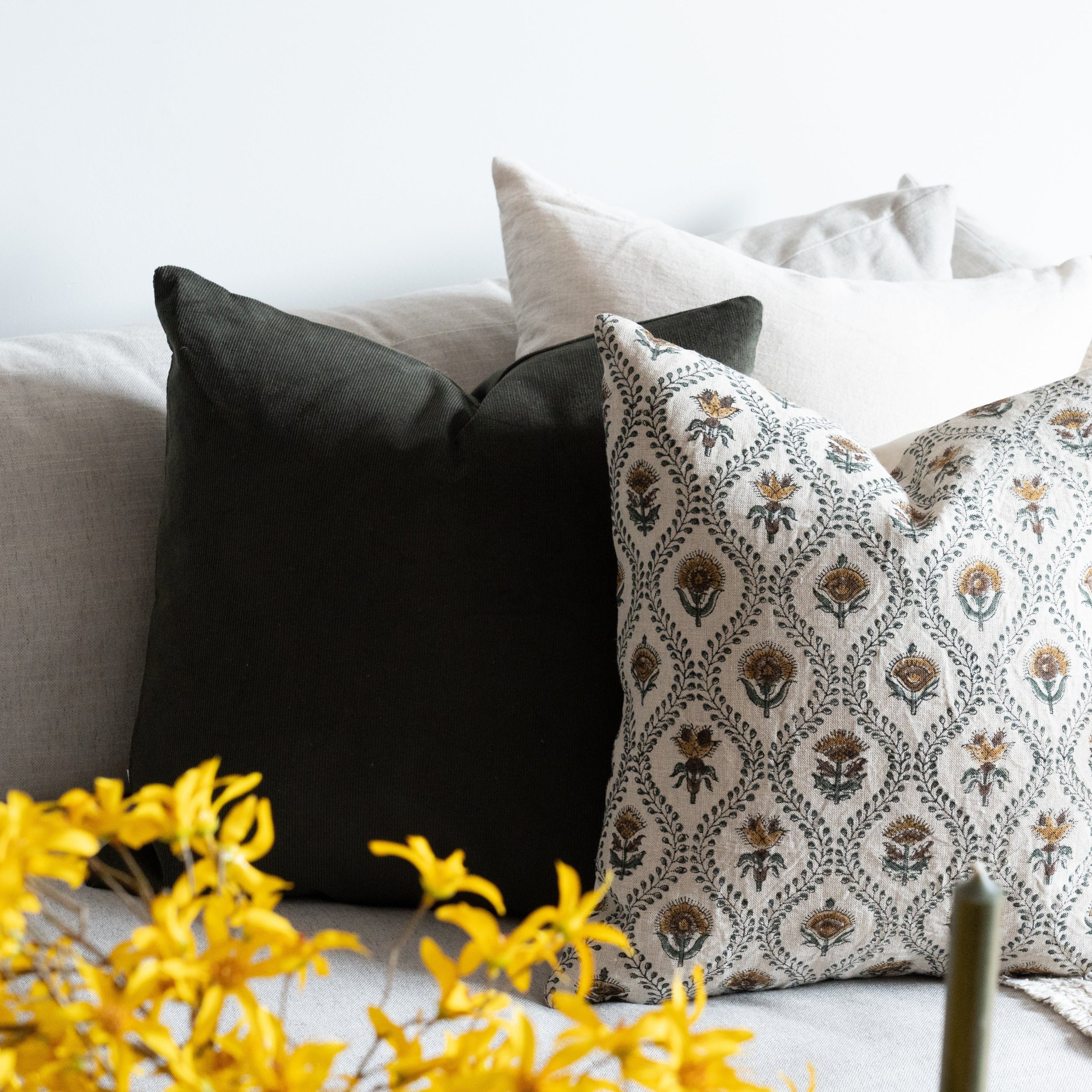 Block print pillow cover styled on couch with green corduroy and linen pillow covers