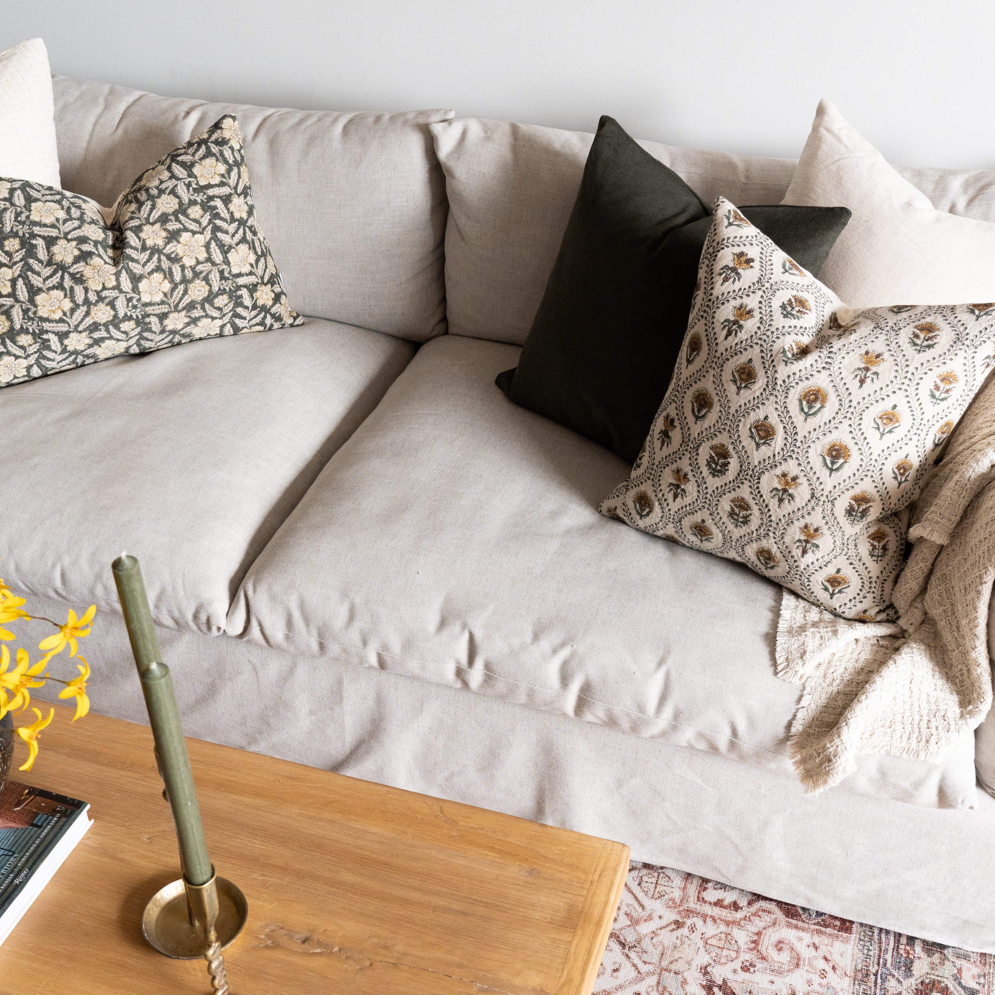 Floral block print pillows styled on beige linen couch with green corduroy pillow accent.