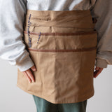 Tan utility apron worn by model